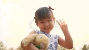 可愛的亞洲小女孩抱著泰迪熊在公園里感受愛情.
