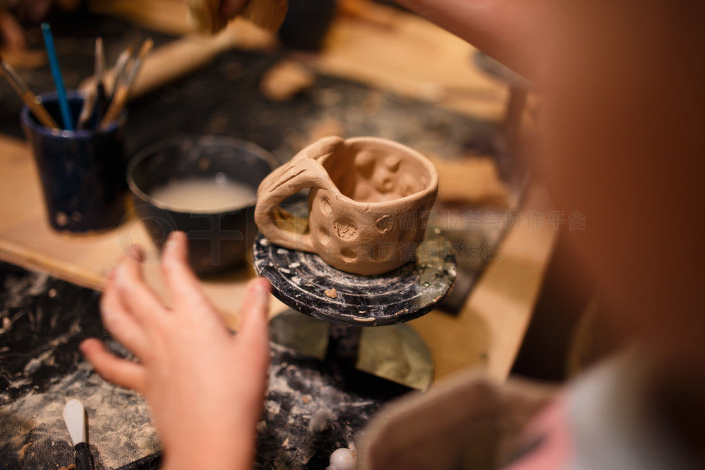 在陶器作坊用红土做杯子的小女孩。在陶器作坊用红土做杯子的小女孩