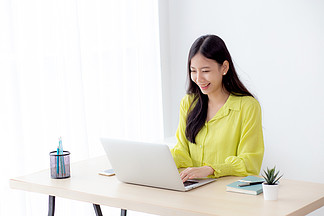 年輕的亞洲女商人在家庭辦公室的辦公桌上使用筆記本電腦，自由職業者在桌上的筆記本上尋找和打字，女性在線學習的生活方式，商業和教育理念。