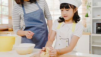 早上，帶著學齡前兒童的快樂微笑的亞洲年輕日本家庭在現代廚房的家中享受烹飪糕點或餡餅作為早餐的樂趣。做面包店揉面團和烤餅干。