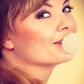 糖果和糖果。樂趣和快樂。年輕的金發女孩玩甜食。快樂的女人咀嚼白色口香糖制作氣球。金發女孩口香糖制作氣球。