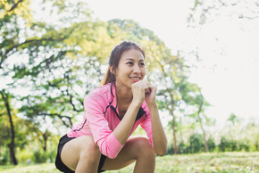 年輕的亞洲女人做深蹲鍛煉以增強她的美感。下午，年輕的亞洲女性在公園周圍的綠樹和溫暖的陽光下深蹲鍛煉以增強她的美麗身體。年輕女子在公園鍛煉。戶外運動。
