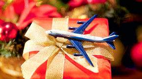 玩具飛機的特寫照片躺在帶金色絲帶蝴蝶結的圣誕禮盒上。寒假旅行的概念。玩具飛機的特寫圖像躺在帶金色絲帶蝴蝶結的圣誕禮品盒上。寒假旅行的概念