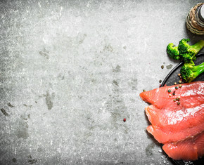 煙熏三文魚片配西蘭花和鹽。在石頭背景上。熏鮭魚片配西蘭花和鹽。