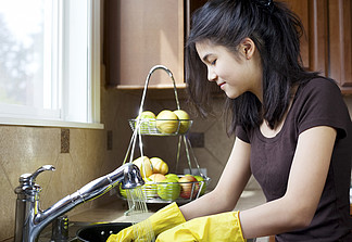 十幾歲的女孩洗碗在廚房的水槽
