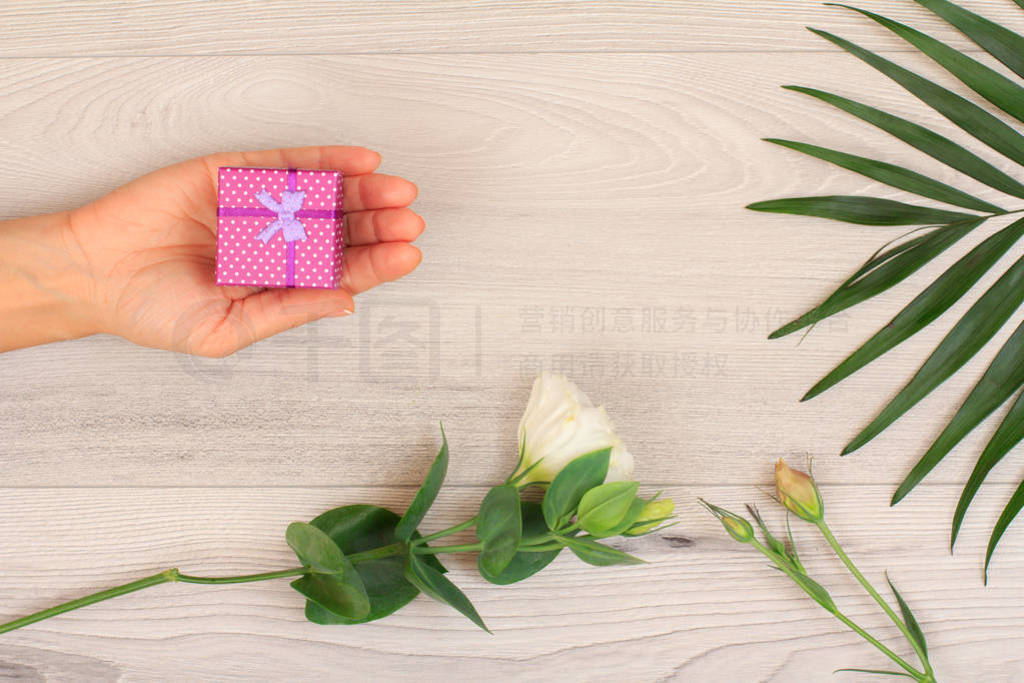 s hands holding a gift box on gray wooden background with beauti