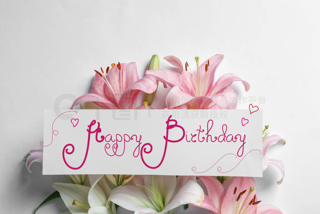 Beautiful lily flowers and card with text Happy Birthday on ligh