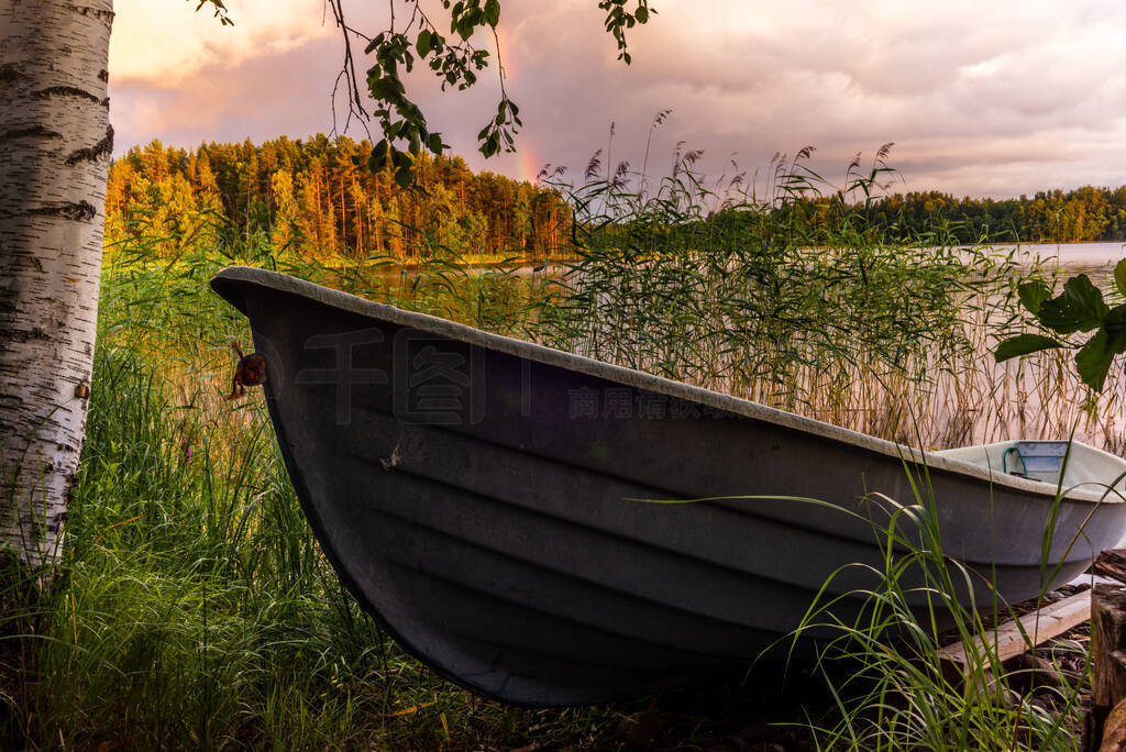 A wooden rowing boat at Sunset on the shores of the calm Saimaa