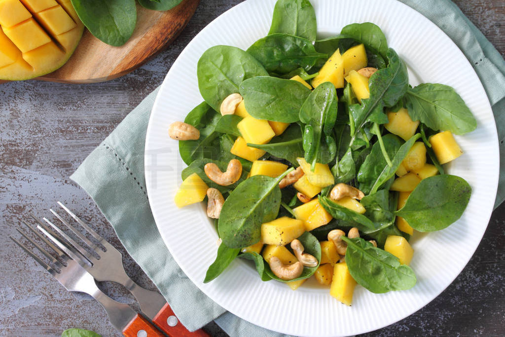 Diet menu, Vegan food. Healthy salad with spinach, mango, pecan