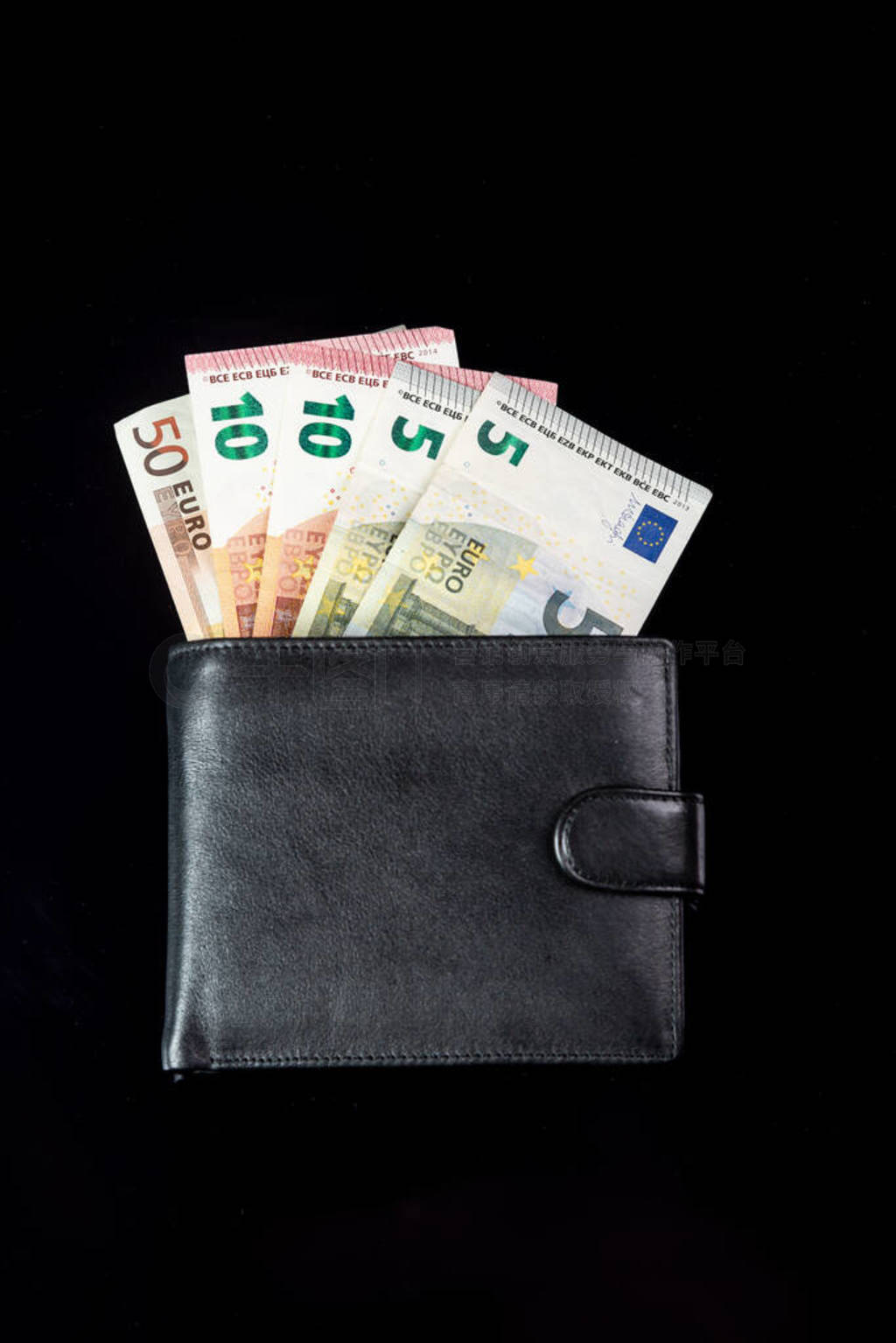 Money euro notes stick out from a black wallet on a black backgr