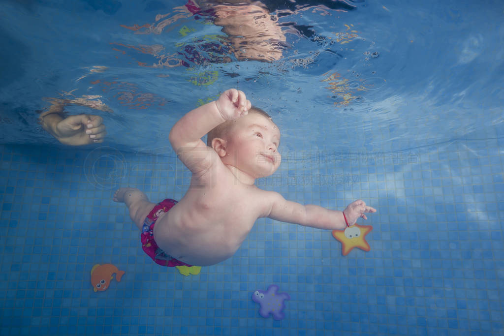 Little baby learns to swims underwater. Baby swimming underwater