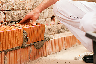 瓦工正在砌砖砌墙 他正在用抹子从接缝中拔出水泥浆这个人真的 i i>