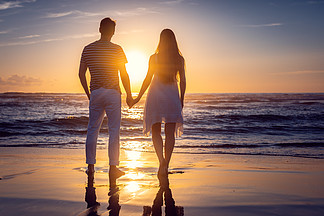浪漫的情侶在假期中牽手站在海邊的海灘上