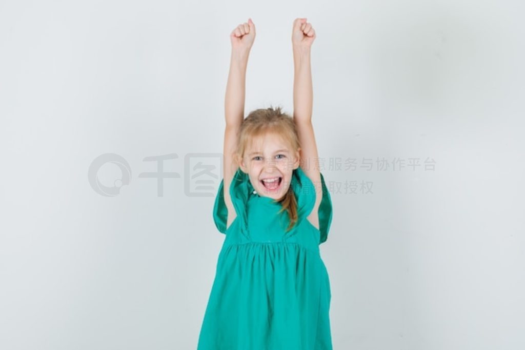 穿绿衣服的小女孩举起双臂，大喊大叫，看上去很高兴