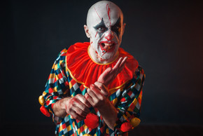 瘋狂的血腥小丑握著人的手，手指在他的牙齒在萬圣節服裝，瘋狂的瘋子化妝的男人