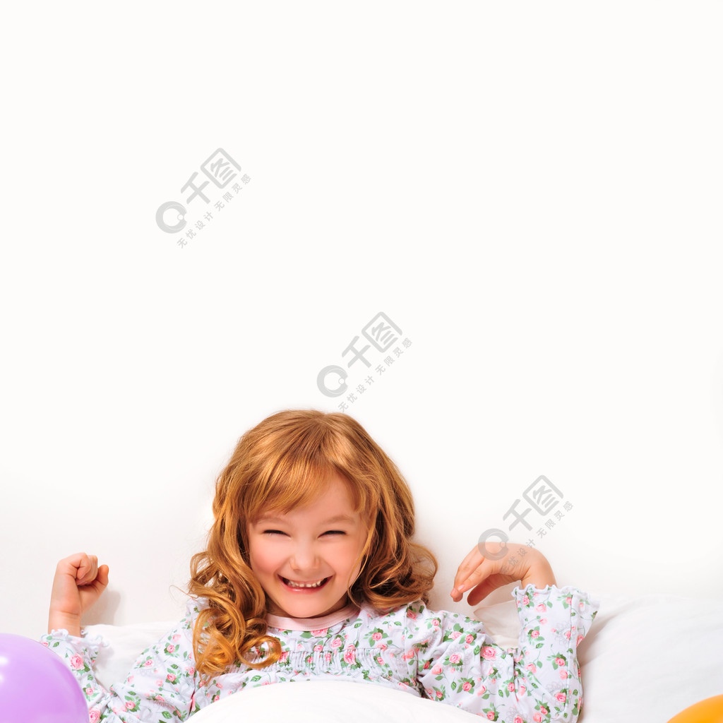 笑脸小女孩躺在床上被彩色气球包围