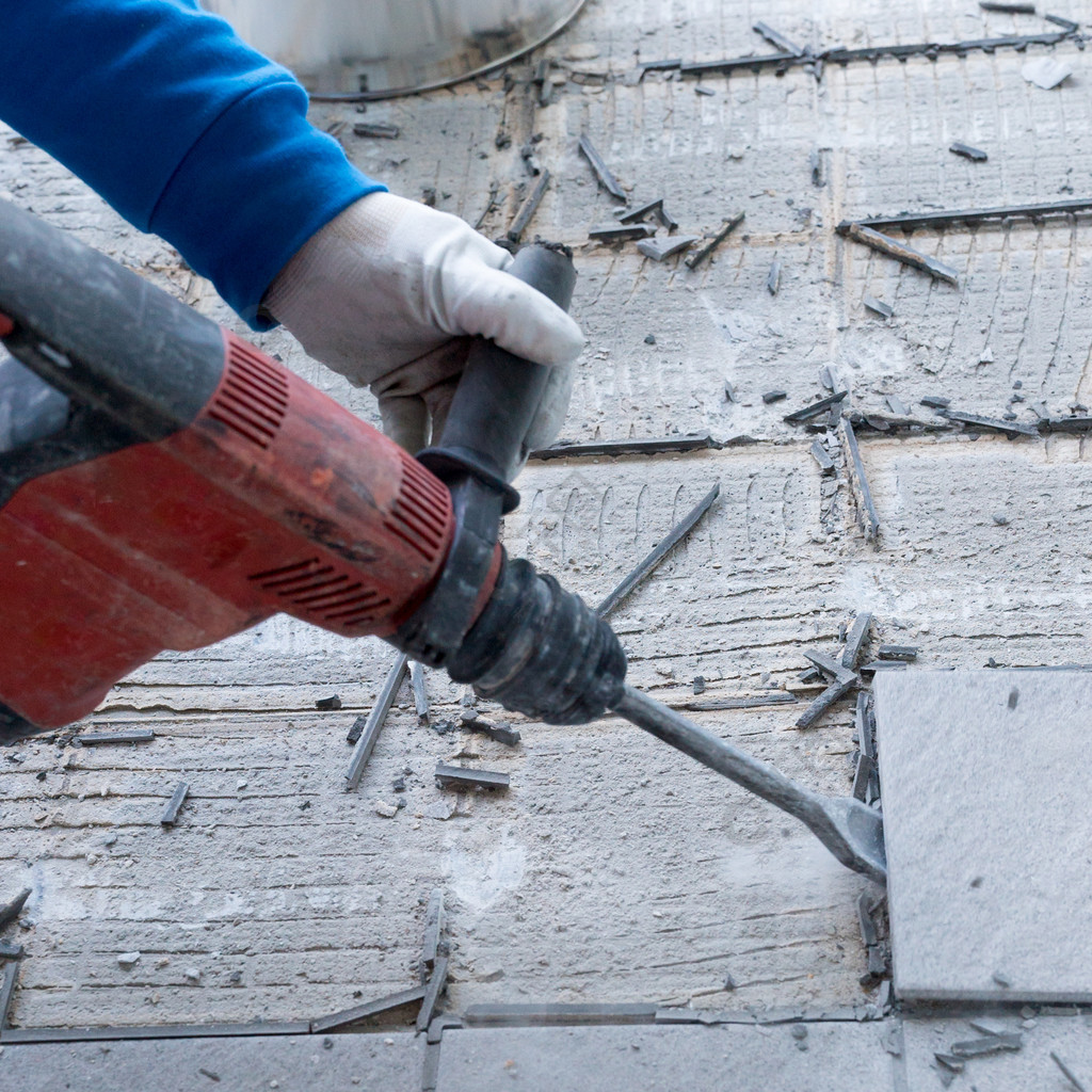 一名建筑工人在装修工作中使用手持式拆除锤和破墙器去掉并去除旧地砖