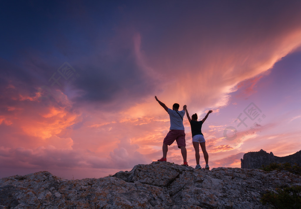 山峰的轮廓男子和女孩在美丽的阴云密布的天空背景人的轮廓一对旅行