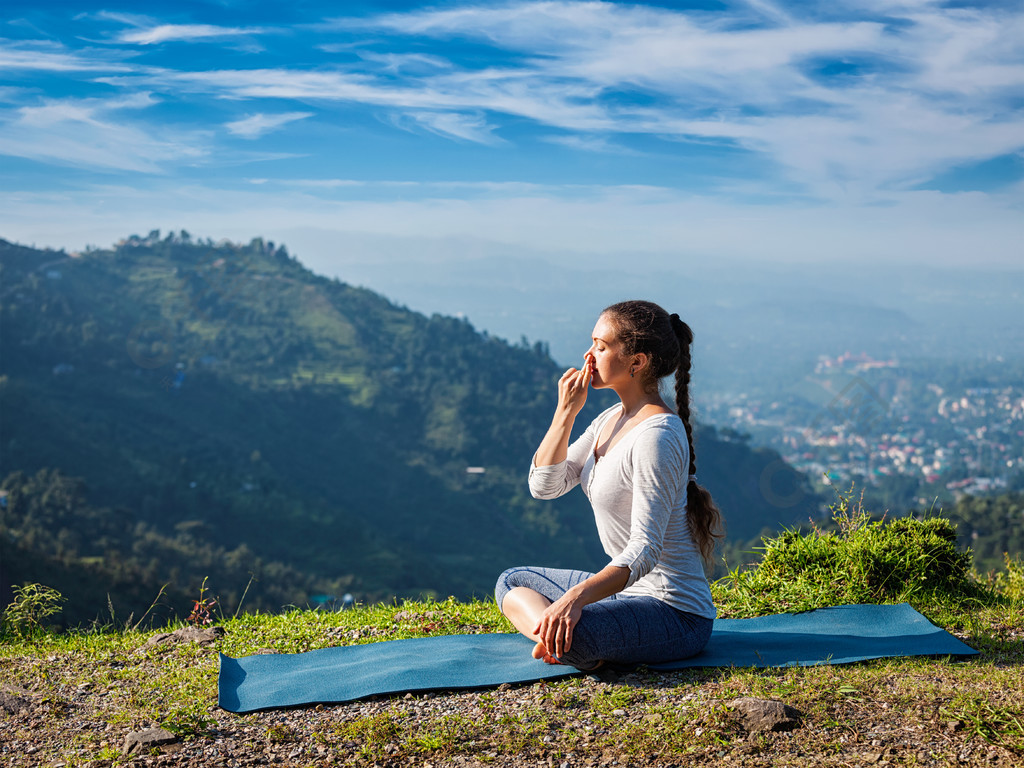 妇女在喜马拉雅山在日出的早晨实践在莲花姿势padmasana的pranayama