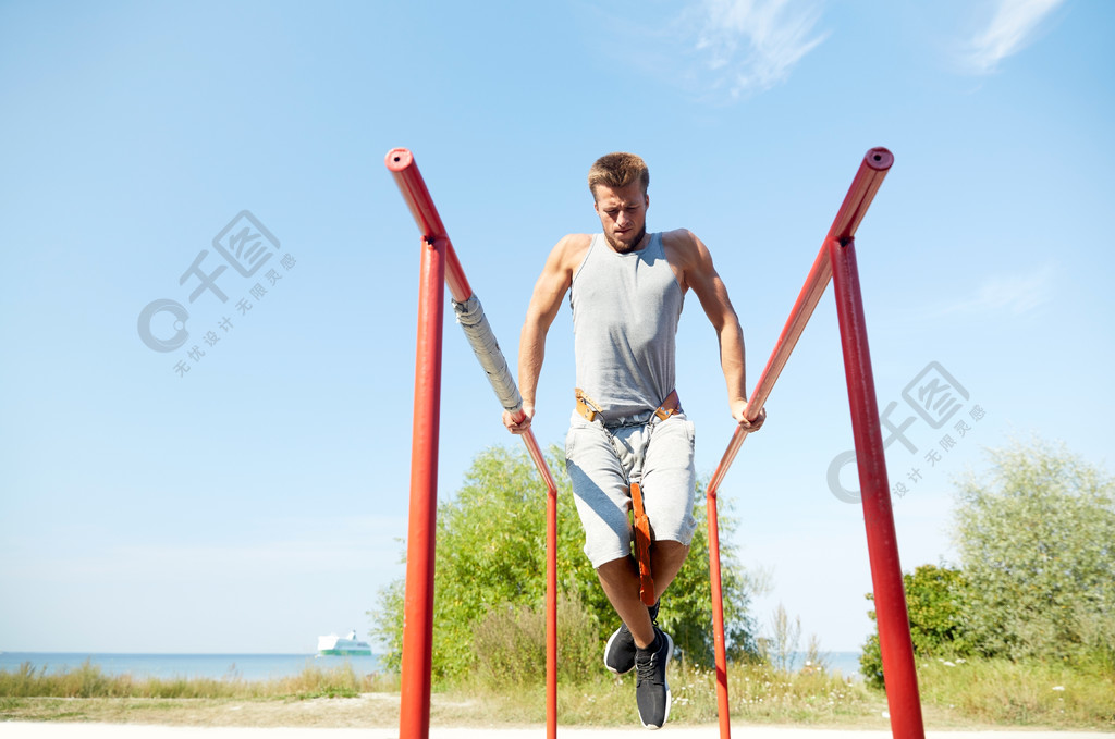 健身运动锻炼训练和生活方式的概念做肱三头肌的年轻男子蘸双杠在户外