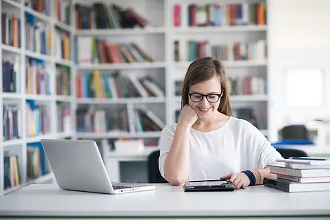 女学生在图书馆学习使用便携式计算机并在互联网上搜索信息