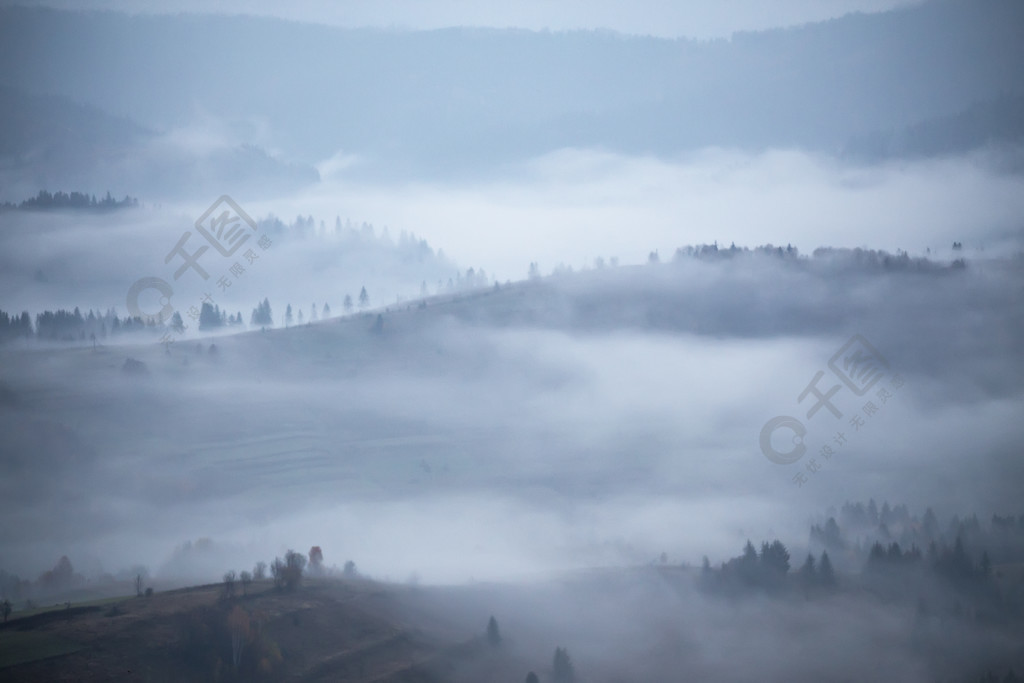 秋天的雨和雾在山上在小山和森林的早晨雾山顶周围有浓雾秋天背景