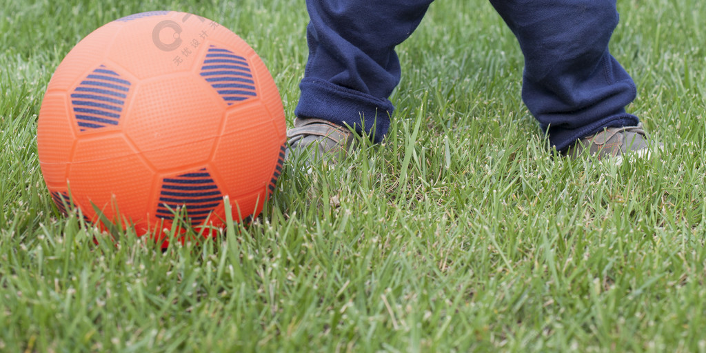 可爱的中国小男孩在草地上踢足球