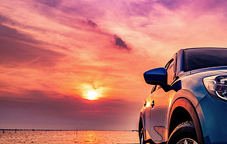 藍色緊湊 Suv 汽車與運動和現代設計在日落時停泊在海邊的混凝土路面。環境友好型技術。商業成功概念.