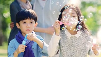 亚洲 小女孩 和 男孩 兄妹 吹 泡泡 在 公园 与父母从后面看