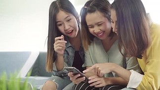 亚洲女性使用智能手机在家里的客厅里查<i>看</i>社交媒体