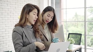 两位亚洲年轻的创意女商人拿着一杯咖啡
