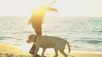年轻男子和他上海滩慢动作的狗玩