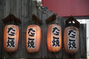 日式餐厅前挂着日式灯笼，灯笼上的日文是章鱼烧日本料理”。