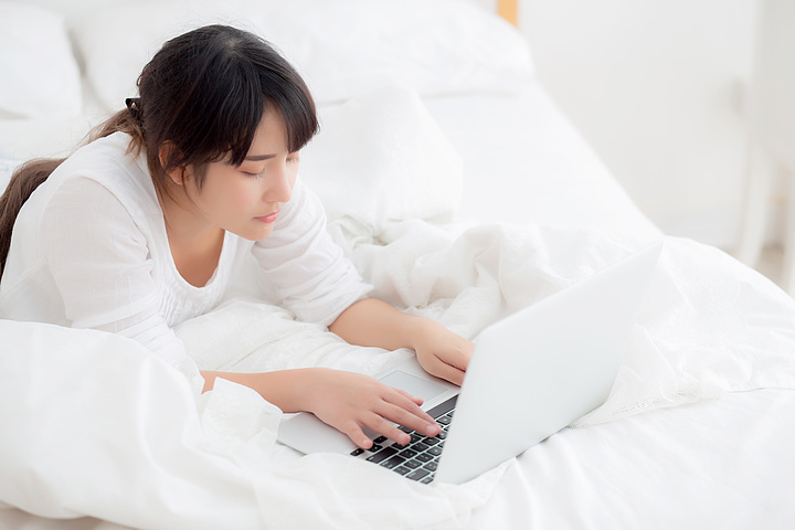自由职业者与工作的女孩笔记本电脑,通信概念躺在床上
