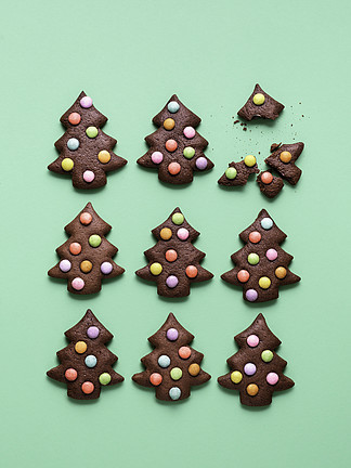 圣诞节烘<i>烤</i>用巧克力姜饼曲奇，树形，用聪明的人装饰，在绿色背景，对称地显示。