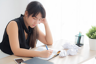 美丽的亚洲女人累，并强调与伏案写作劳累过度，女孩不担心在办公室，自由职业者和经营理念与笔记本电脑的想法和皱巴巴的纸。