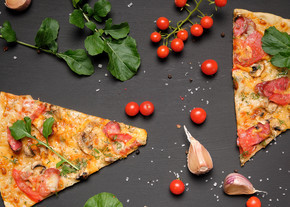 三角形烤披萨，配蘑菇、熏香肠、西红柿和奶酪，黑色背景，平躺
