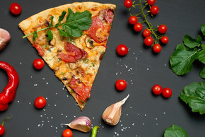 三角形烤披萨片，配蘑菇、熏香肠、西红柿和奶酪，旁边是新鲜的芝麻菜绿叶，黑色背景，平躺