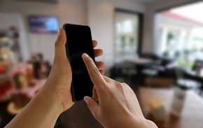商人的手拿着智能手机，用手指点空餐厅和咖啡馆背景上的屏幕