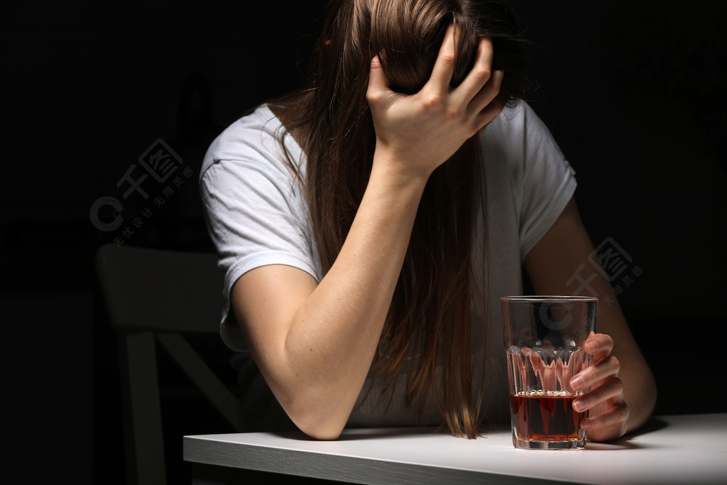 女人在厨房里喝酒患有强烈头痛或偏头痛的年轻女子坐在厨房里喝杯