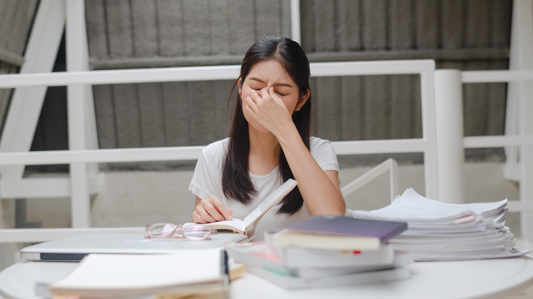 在大学校园概念的讲台上努力学习知识时,年轻的本科女孩压力累了.