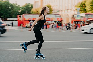 <i>保</i>持健康和健康的户外活动。体型良好的欧洲女性穿着运动服，穿着直排轮滑鞋，骑着滚轮，有积极的休息。运动的生活方式概念