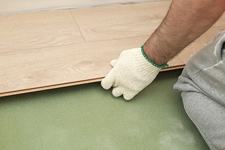 在房间内安装复合地板或镶木地板，在绿色泡沫底座上安装木瓷砖的手工细节。在房间内安装层<i>压</i>或镶木地板，在绿色泡沫底座上安装木瓷砖的手工细节