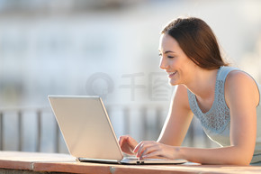 一个快乐女孩在阳台墙上用笔记本电脑写字的肖像