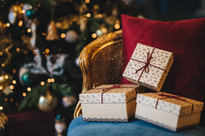 包装好的礼品盒的图片躺在扶手椅上，装饰着新年树背景。为假期做准备。美丽的圣诞树，里面有花环和礼物