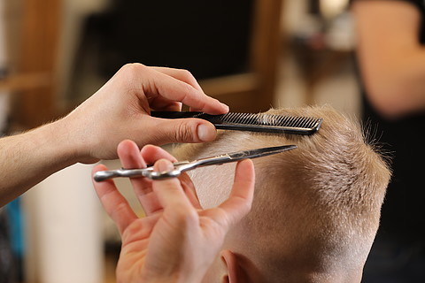 男人手在理发店梳理孩子男孩头发的特写镜头