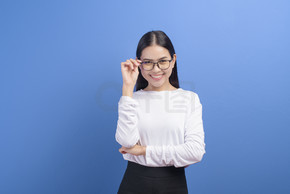 蓝色背景工作室戴眼镜的年轻女性肖像，医疗保健概念。蓝色背景工作室戴眼镜的年轻女性肖像、保健概念