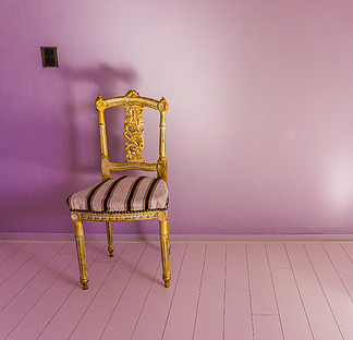 空荡荡的豪华古董椅站在一间空荡荡的房间里，房间里有粉红色的层<i>压</i>板和紫色的墙壁背景