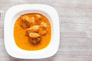 印度菜 — Murg Makhan <i>Masala</i> 用辣番茄和奶油咖喱酱在木桌上的白碗里烤鸡块