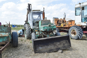 俄罗斯，Temryuk-2015 年 7 月 15 日： 拖拉机。推土机和平地机。带挖土桶的拖拉机。这张照片是在 Temryuk 郊区的一个农村车库里的一个拖拉机停车场拍的。 拖拉机有一个挖土用的桶。